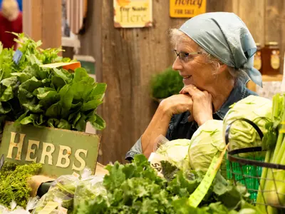 vendor at booth surrounded by fresh herbs