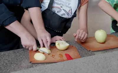 Close up of kids' hands cutting apples
