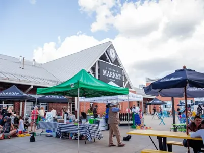 vendor tables in front of the kitchener market building with people walking around