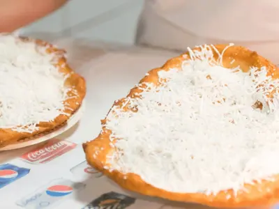 two hands holding two pastries covered in shredded cheese