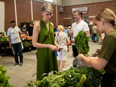 market vendor with fresh produce and market shoppers